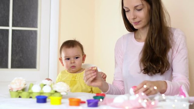Happy Easter family mother and baby painting eggs at home seasonal traditions with bunny ears