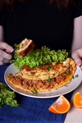 Woman is eating a piece of omelette with a fork. Breakfast meal
