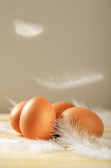 Chicken eggs with flying white feathers on wooden background. Healthy nutritious food. Easter...