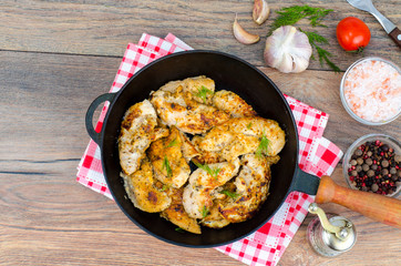 Pan with fried pieces of meat on wooden table