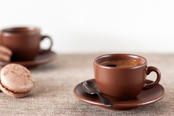 On the table is a cup of coffee with macaroon
