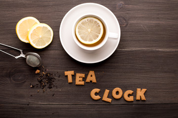 Black tea with lemon and cookies tea on a wooden background