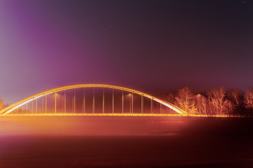 Fototapeta na wymiar Abstract photo of a bridge over a frozen river with fog at night 