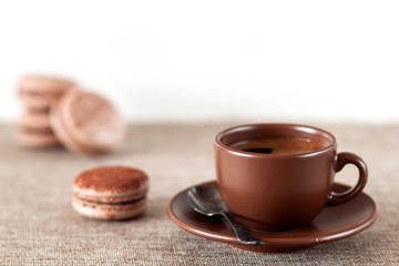 On the table is a cup of coffee with macaroon