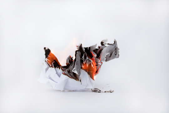 Papel blanco quem&aacute;ndose en fondo blanco. Quemar ideas. Fondo conceptual