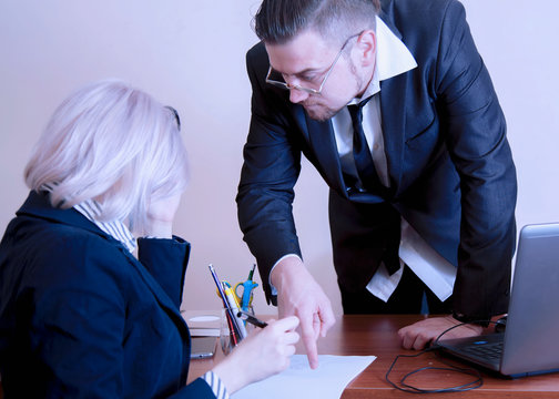 Business people having a team meeting. Boss businessman pointing to a document where his employee is about to sign.