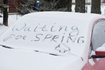 Waiting for spring. The inscription on the windshield of a red car. The concept of cold spring, the end of winter