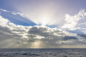 Obraz premium The clouds above the sky creating an amazing view of lines and formations trying to close the sun rays that scape from the clouds creating a moody sky with the rays of light illuminating the scene