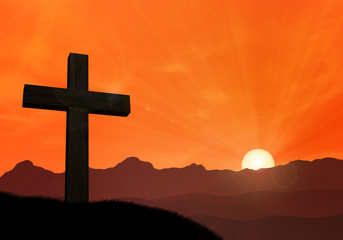 Cross of jesus in front of mountains at sunset