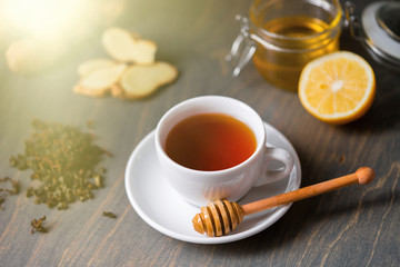 Cup of tea with lemon, ginger, honey and honey stick on wooden rustic table .