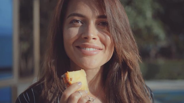 woman licks slice of pineapple