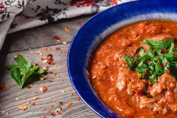 Veal meat with spices in a tomato sauce, veal meat in tomato sauce with onion, garlic, chili peper on the wooden background. boiled meat and fresh tomato top view