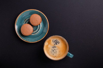 Blue cup of coffee and macaroons on the dark wooden table. Coffe break. Top view. Flat lay