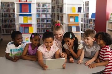 Front view of schoolkids studying together on digital tablet at