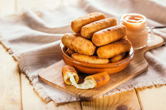 Cheese fingers, typical Venezuelan appetizer called tequeños accompanied with a pink sauce on a wooden board