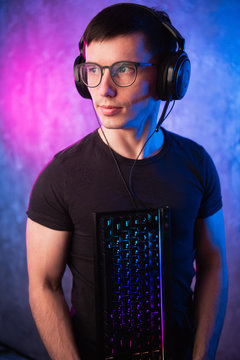 Computer nerd with keyboard over colorful pink and blue neon lit wall