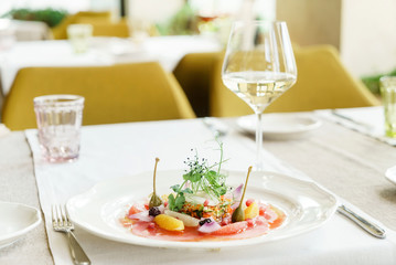 tuna carpaccio and white wine on the table in the restaurant