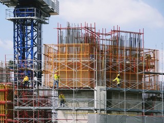 Big construction site with worker ware safety helmet and safety sling working on high scaffolding