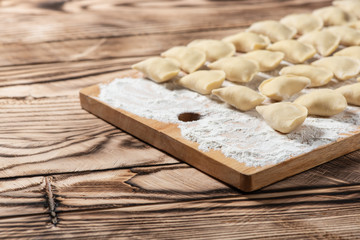 Raw dumplings on wooden cutting board, is ready to boil. Also known as Vareniks. Ukrainian traditional cuisine