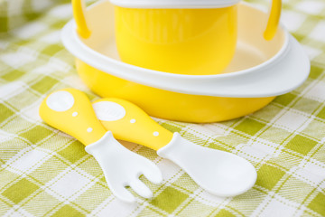 Set of yellow empty dishes for baby. Tableware for the first feeding, soft focus background