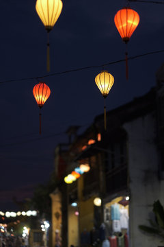 Multi-colored lights hanging on the wires of the decorative street illumination of the night city. Vietnam