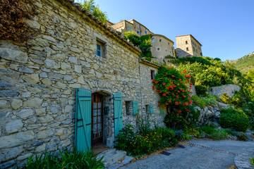 Fototapeta na wymiar Rue et façades des maisons de village de Brantes, Provence, France. Fleurs de trompette de Virginie (Campsis radicans).