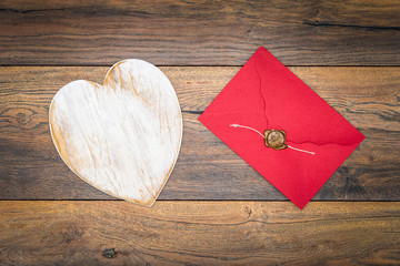 Retro classic Valentine’s Day cad, large white painted wooden hart, isolated, red envelope with wax seal, on vintage oak panels – top view