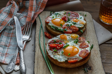 Toasts with eggs and tomatoes on cutting board