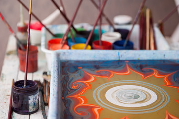 Paint brushes Ebru technique in cans of paint  