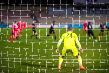 Football goalkeeper, soccer game in background