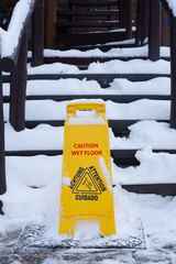 Sign cautiously slippery floor on a street in winter near the stairs. Red text.