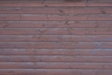 Wooden wall painted with brown paint with traces of blue paint from a can. The texture of the wooden wall.