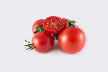 Fivefresh cherry tomatoes isolated on white background. Tomatoes are stacked. One is cut in half. Close photo