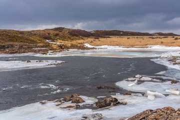 Dunkle Wolken am Fluss im Winter in Island