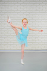 Cute little ballerina in blue dress dancing at ballet class.