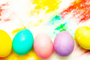 Colorful Easter eggs frame border on multicolor painted background. top view, copyspace