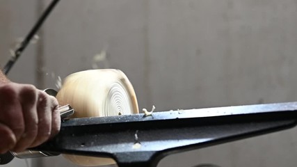 handicraft man edits a rotating piece of wood on turnery machine