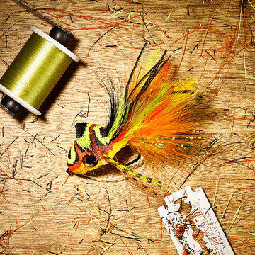 A diver fly for fly fishing on a wood background