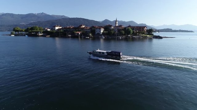 Aerial footage of ferry water taxi moving fast over Lake Maggiore in northern Italy also showing Isola dei Pescatori or Superiore which is the most northerly of the three principal Borromean Islands
