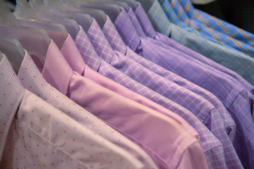 Male wear on plastic hanger. Official wear for men in department store. Pastel shirts on hangs for sale in shop.