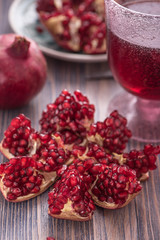 Pomegranate juice in a glass with fresh pomegranates around with scattered seeds on rustic wooden background 6