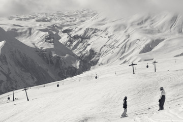 Two snowboarders descend on snowy ski slope