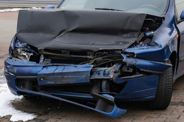Detail of a crashed blue car after a horrible frontal traffic accident