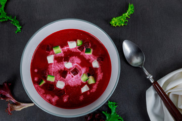 Bowl of cream soup of red beets with a fresh beet root and leaves