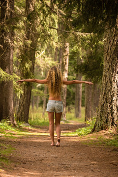 Ragazza a piedi nudi nel bosco con braccia aperte