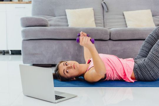 Young girl looking at laptop and doing exercises at home.