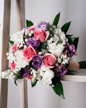 Wedding bouquet on white stairs. Red and pink roses. Flower photography on white background