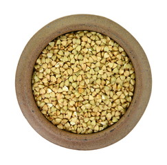 buckwheat grain in a clay bowl isolated on white background close up. Top view. Ancooked buckwheat.