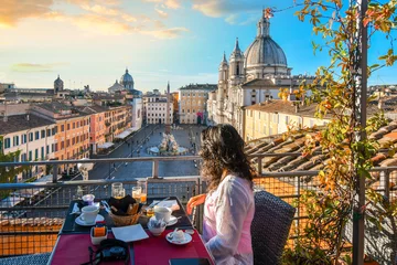 Foto auf Acrylglas Rome Eine Frau genießt den Blick auf Rom, Italien und die Piazza Navona, während sie an einem frühen Sommermorgen ihr kontinentales Frühstück von der Dachterrasse eines Luxushotels beendet.