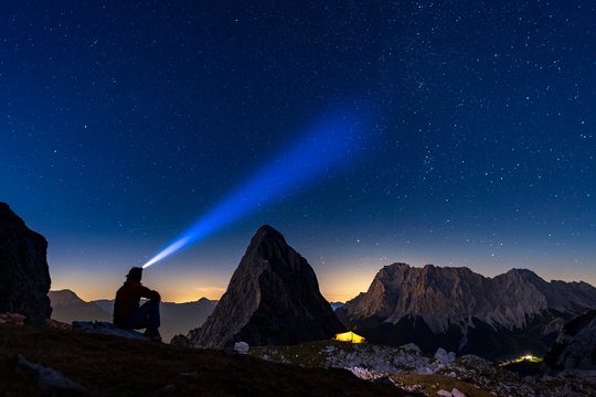 Summit of the Sonnenspitze with mountaineer and tent as well as Zugspitze in the background with blue hour and starry sky, Ehrwald, Ausserfern, Tyrol, Austria, Europe